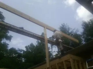 Carpenter setting a ridge beam over a new addition frame — Ice Dam Removal by Roofing Brothers in Red Oak