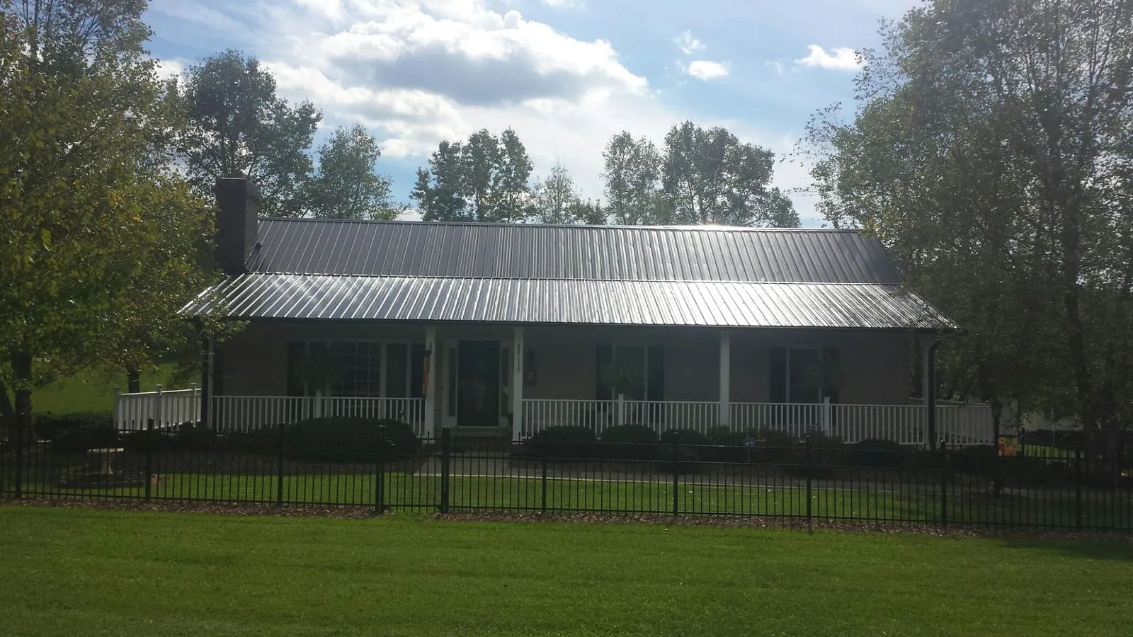 Gray metal roof on a brick ranch with a full width front porch — Gutter Guard Installation work by our crew in Red Oak