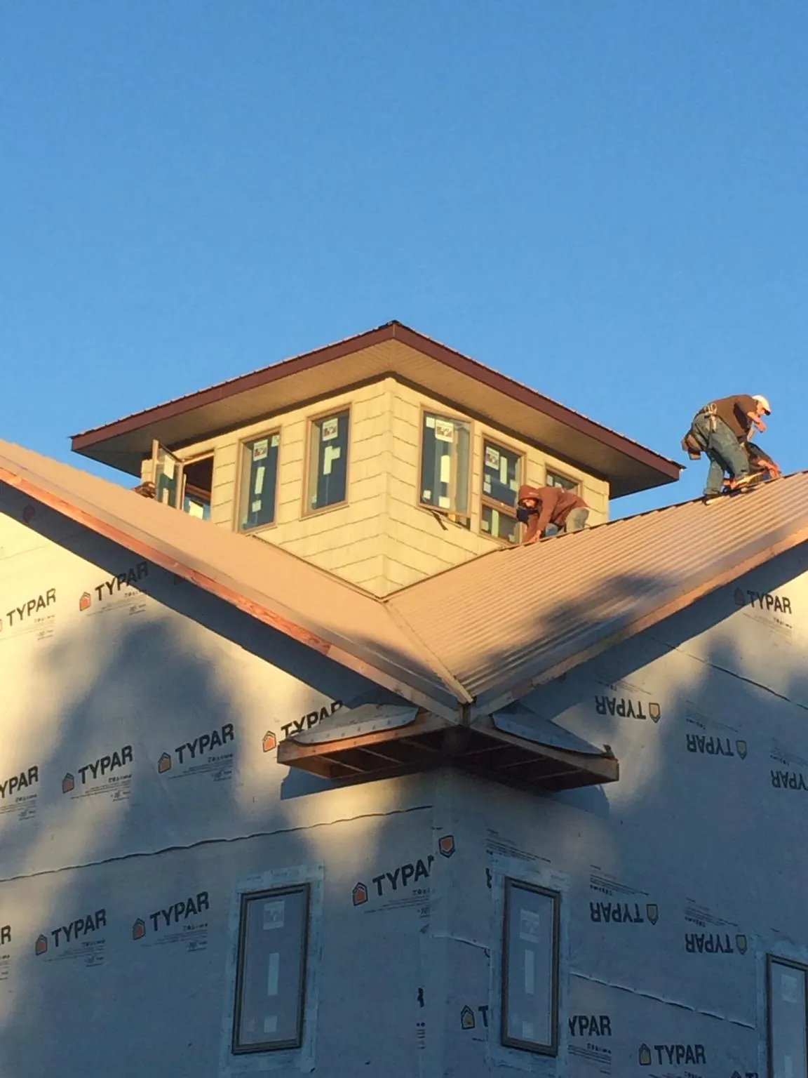 Roofers working around a rooftop cupola on a new metal roof at sunset — Roof Waterproofing in Red Oak by Roofing Brothers